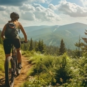 Mountainbikerin fährt im Sommer durch eine Bergwaldlandschaft.