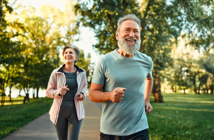 Fröhliches Ehepaar, das gemeinsam an Wettkämpfen teilnimmt und an der frischen Luft joggt. Aktive Menschen in Sportkleidung beim Cardio-Training.
