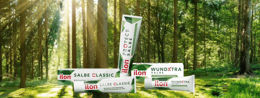 ilon Salbe classic, ilon Protect Salbe und ilon WundXtra Salbe angeordnet vor einem Waldhintergrund
