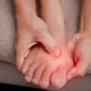 Nahaufnahme eines Fußes. Durch einen roten Verlauf wird ein geschwollener Zeh signalisiert