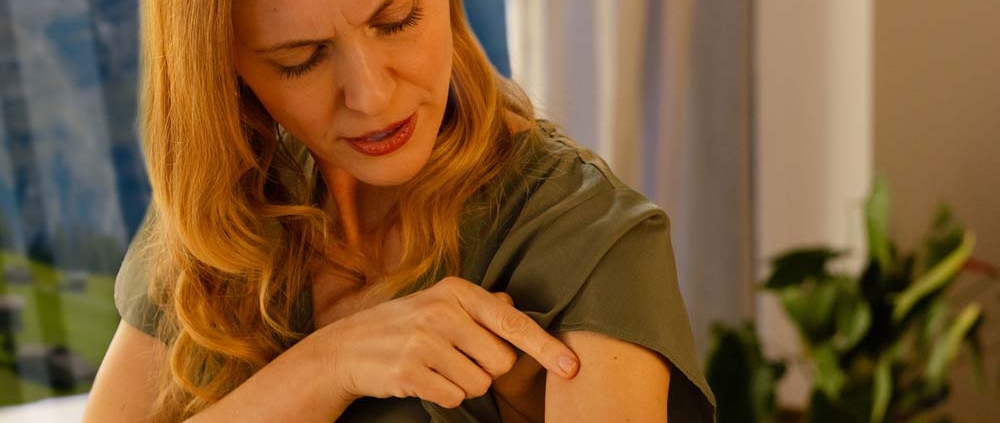 Frau zeigt auf entzündete Hautstelle