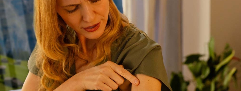 Frau zeigt auf entzündete Hautstelle