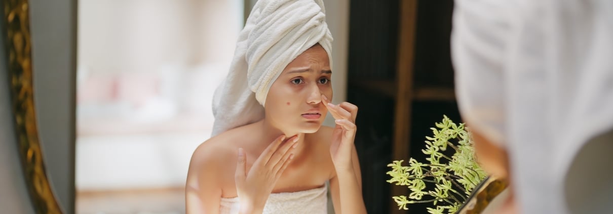 Junge Frau im Bad mit einem sichtbaren Pickel im Gesicht